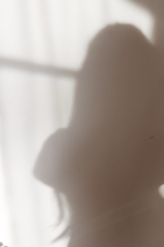 Der weiche Schatten einer Frau hinter einem hellen Vorhang.